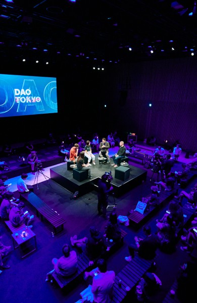 DAO Tokyo 2024 Real World Assets panel on stage at Kanda Myojin Shrine, with the DAO TOKYO screen behind and a packed audience